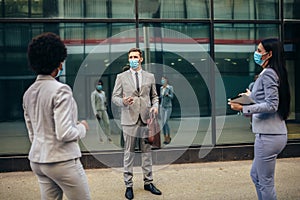 Employers standing in social distance wearing face mask looking at each other and talking