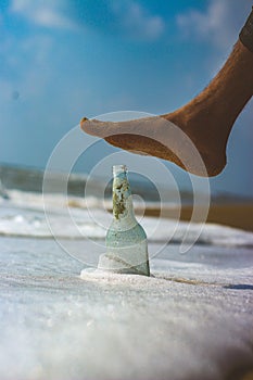 Emply bottle on the beach sand with water waves