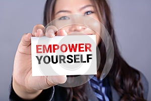 EMPOWER YOURSELF message on the card shown by a businesswoman