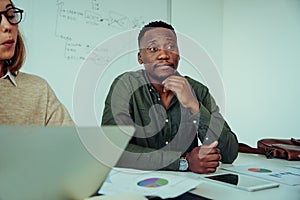 Empowered business man listening to ideas presented by colleagues sitting in meeting in board room