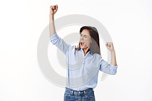Empowered triumphing joyful middle-aged woman celebrating success, fist pump victory gesture, close eyes yelling oh yeah