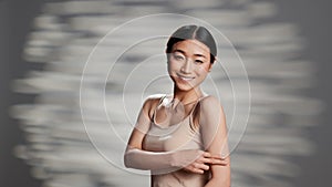 Empowering woman using body cream on camera