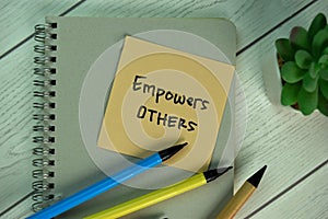 Empowers Others write on sticky notes isolated on Wooden Table