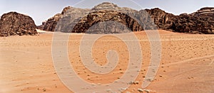 The emptiness of the great desert in the nature reserve of Wadi Rum, with large mountains of red sandstone in the background and t