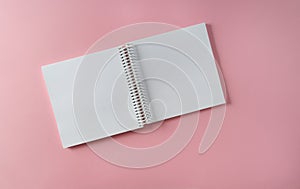 An empty A4 notebook in expanded form on a pink paper background, top view,mockup