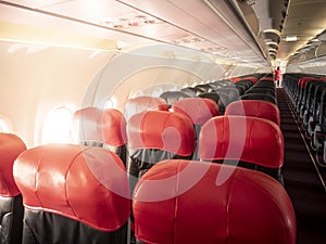 Empty aircraft cabin with female cabin crew working in galley. premium and economy seat row in cabin. red and black seat. Outstand