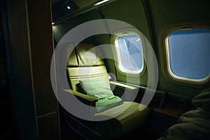 Empty airplane leather seat and windows of first class aircraft, illuminating the cabin with soft overhead lights. Generative AI