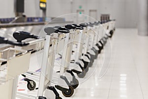 Empty airport luggage carts parking behind warning line in baggage claim area in terminal.