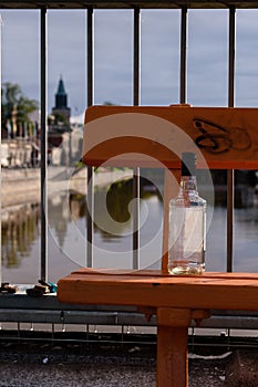 Empty alcohol bottle on a bench alongside the river in city