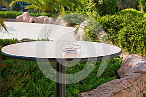 Empty ashtray on one legged, round table in the garden