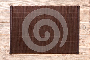 Empty Asian Food Background. Dark Bamboo mat on brown wooden background top view with copy space flat lay