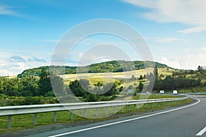 The empty asphalt road and blue sky with white clouds on the sunny day. Classic panorama view of road through fields