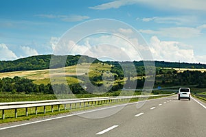 The empty asphalt road and blue sky with white clouds on the sunny day. Classic panorama view of road through fields