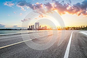 Empty asphalt road and city buildings skyline at sunset in Suzhou