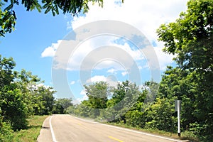 Empty asphalt road in forest on blue sky