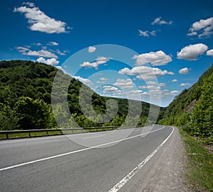 Empty asphalt road highway in the forested mountains, on sky