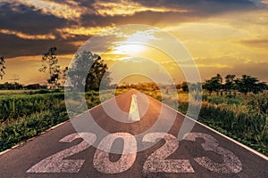 Empty asphalt road and New year 2023 concept. Driving on an empty road to Goals 2023 with sunset