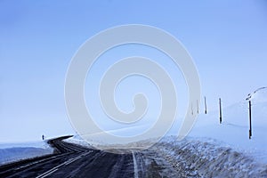 Empty asphalt road stretching beyond the horizon. Snowy landscape. Power line