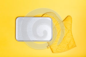 Empty bake plate place over yellow oven gloves on yellow color background. Mockup for food banner