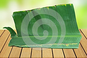 Empty Banana leaf on perspective wooden table on top over blur background. Can be used mock up for montage products display or