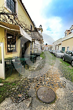 Empty bar terrace on Narrow street of Lisbon in a cloudy day