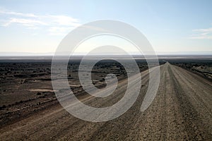 Empty barren dirt road leading through wasteland into the endlessness of Atacama desert, Chile photo