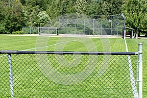 Empty baseball or softball diamond from the back fence and foul line looking towards the grass and trees in Whistler, British