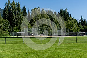 Empty baseball or softball diamond from the back fence and foul line looking towards the grass and trees in Whistler, British