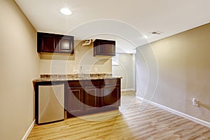 Empty basement room with dark brown kitchen cabinets