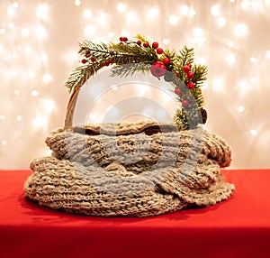 Empty basket with Christmas decor and a scarf on a red background with bokeh lights. Christmas background for design