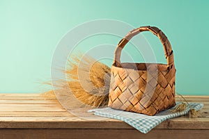 Empty basket with wheat on wooden table over blue background. Harvest mock up for design