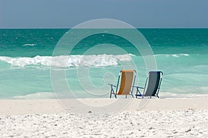 Empty Beach Chairs In The Surf