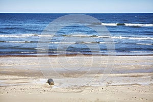 Empty beach with discarded trash can.