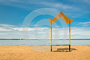 Empty beach with a bench with a canopy on the coast