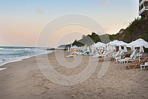 Empty beach on the seaside at the end of resort season with many empty sun loungers and umbrellas in the evening