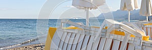 Empty beach at seaside resort with stacked sun loungers and umbrellas