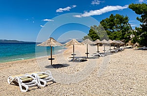 Empty beach with sun loungers and beach umbrellas in Croatian Makarska