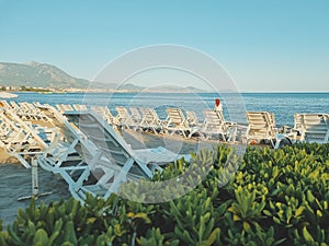 empty beach with sun loungers, lonely woman in headscarf on beach, sea and mountains. Alanya Turkey. soft focus.