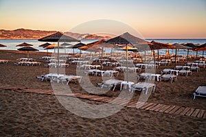 Empty beach with sunshade and deckchair in nice sunrise warm illumination