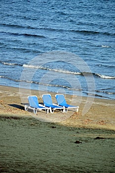 Empty beach with three sun loungers on sand