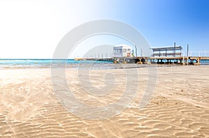 Empty beautiful beach with yellow sand on sunny day/Empty sandy beach. Deserted beautiful beach with lifeguard hut