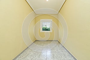 Empty bedroom with barred window overlooking