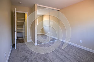 Empty bedroom with mirrored closet doors and carpet