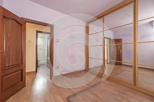 Empty bedroom with mirrored sliding door wardrobe and ligh