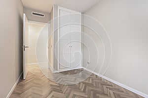 Empty bedroom with white door, built-in wardrobes, herringbone