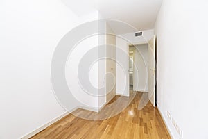 Empty bedroom with white wooden built-in wardrobe doors and ducted air conditioning, white painted walls and wooden floors