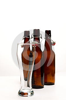 Empty beer glass with beer bottles on white background