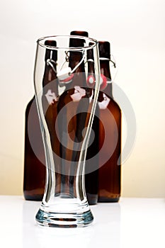 Empty beer glass with beer bottles on white background