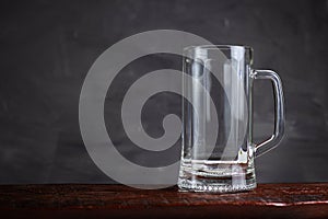 An empty beer glass stands on a wooden table