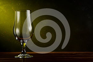 Empty beer glass on a wooden table. Dark background. Drink concept